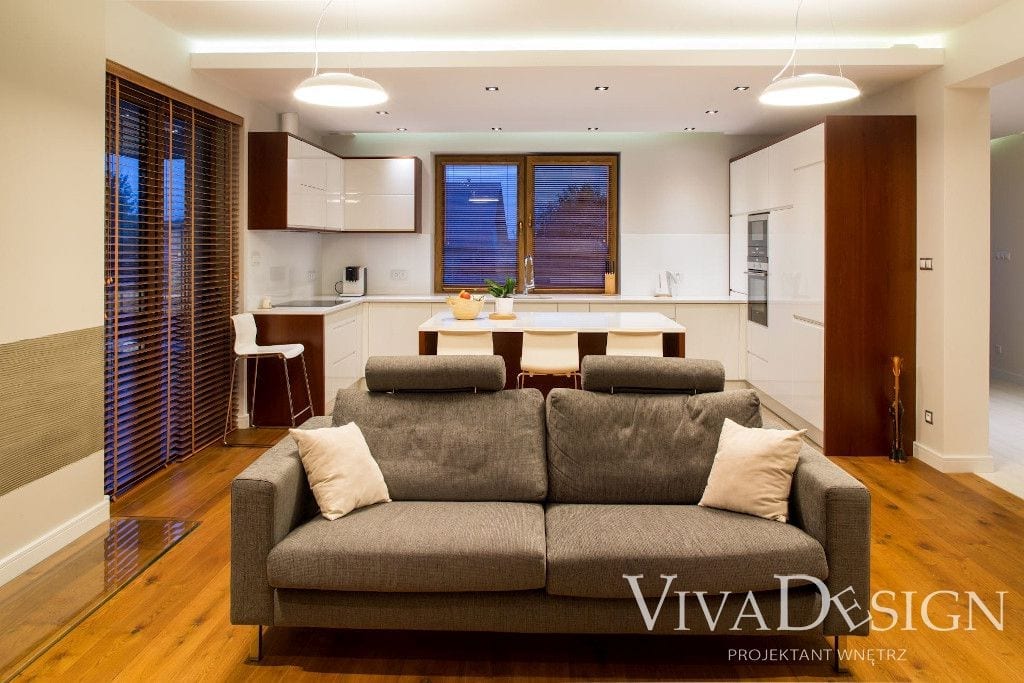 Szara tapicerowana dwuosobowa sofa w salonie na drewnianej podłodze